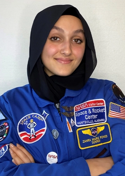A closeup of a young woman, she smiles at the camera