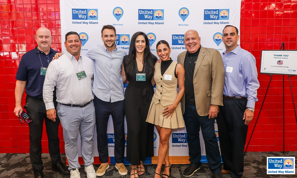 Group of people posing next to a United Way Miami mural