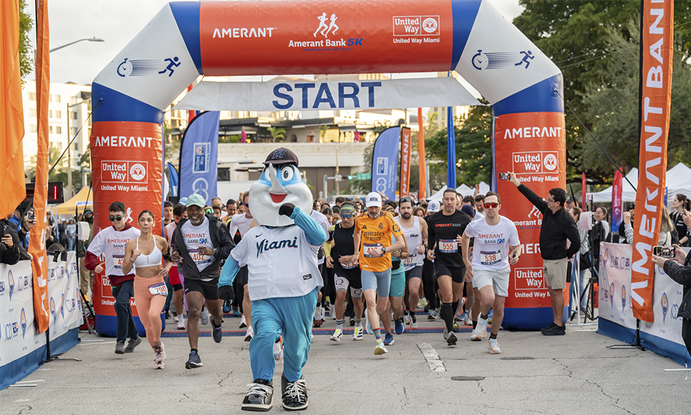 Amerant 5k runners begining their race at the start line with Billie The Marlin in the lead.